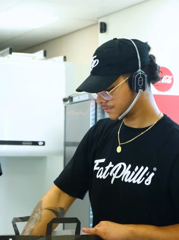 Fat Phill's team member with a headset packing a Drive-Thru order