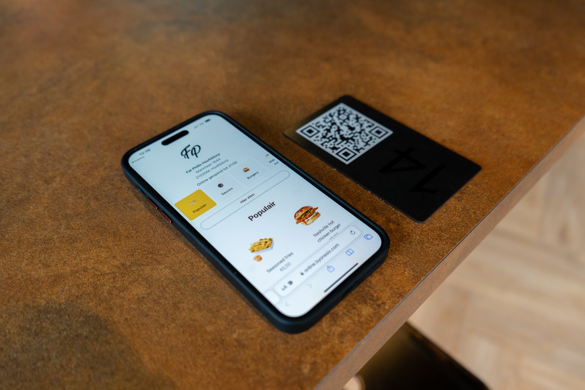 Phone showing the Online Kiosk digital menu next to a QR table card in a hospitality venue