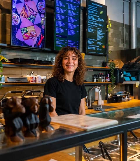 Grlla Kitchen team member behind the counter with Onesix menu screens