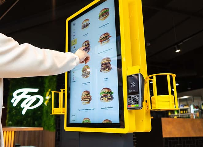 Guest ordering at the yellow Onesix Kiosk at Fat Phill's