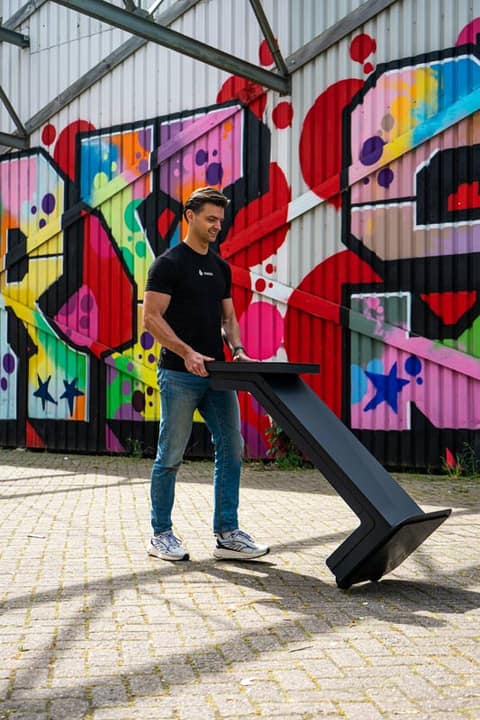 Team member easily moving an Onesix Kiosk in front of a graffiti wall