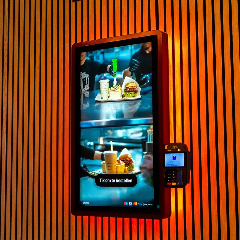 Onesix Kiosk on the wooden wall at Burger ’n Shake, with an orange glow