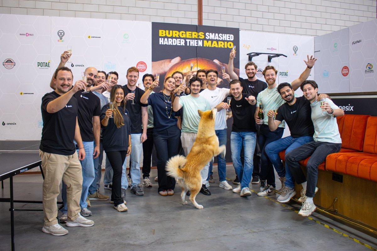 The Onesix team raising a glass of champagne in the Onesix office, with a jumping dog in the foreground
